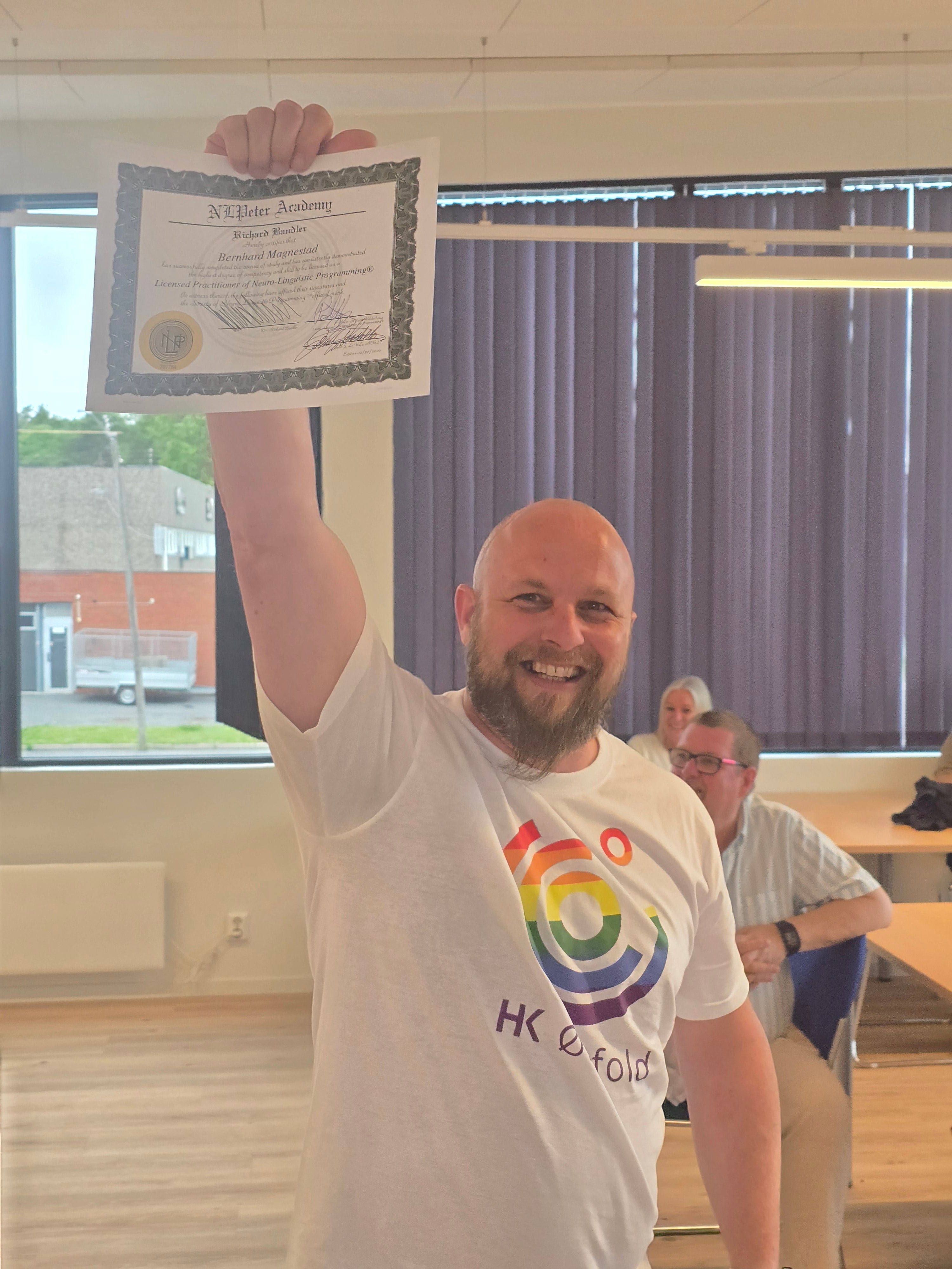Kursdeltaker smiler og holder opp en NLP Practitioner-lisens.