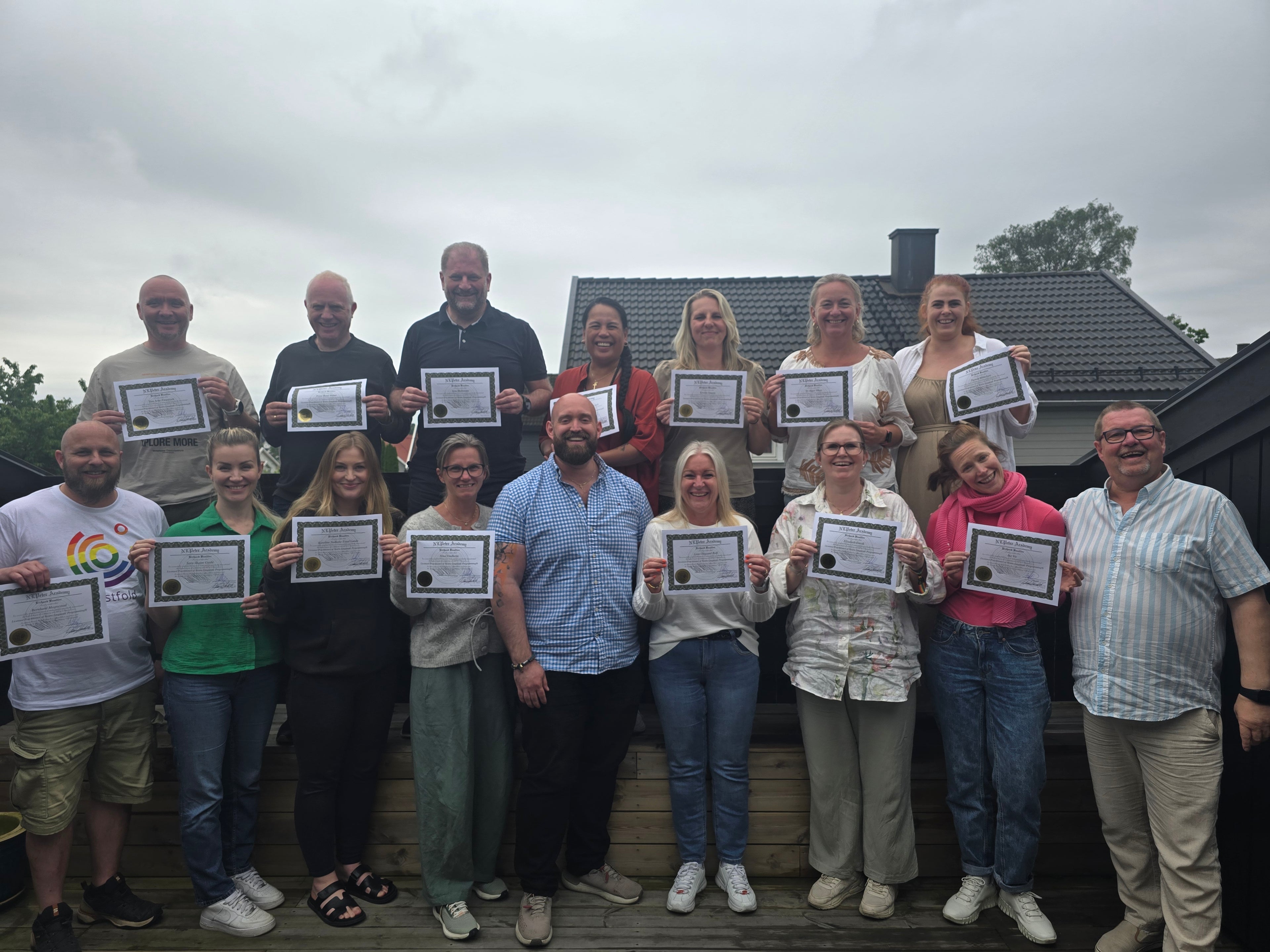Gruppebilde fra NLP Practitioner-utdanningen med deltakere som holder opp lisensene sine.